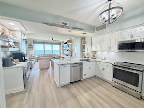 A modern kitchen with white cabinetry, a built-in oven, and a large island with a sink. - Gulf Front with 40' Balcony waiting on you! (Panama City Beach)