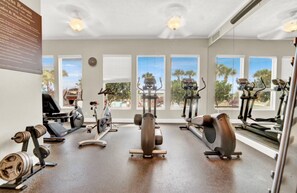 A gym with cardio machines, weight benches, and dumbbells.