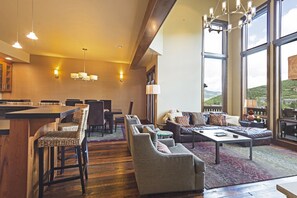 Amplia sala de estar con un ventanal grande, una zona de bar y un conjunto de asientos que incluye un sofá y sillones.