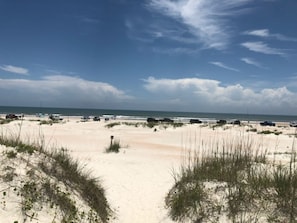 Una playa con dunas de arena y cielo despejado.