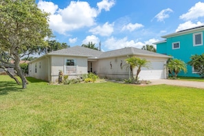 A single-story house with a garage, surrounded by a well-maintained lawn and a tree. - Robin's Nest: Private 4 bedroom Pool home just steps to beach with screen pool (St. Augustine Beach)