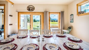 A dining room with a table set for six, large windows, and a view of the outdoors. - Golf Course Mountain Home , Views/Hot Tub/Star Gazing/Ski/Hike/Golf/Gather/Relax (Red Lodge)