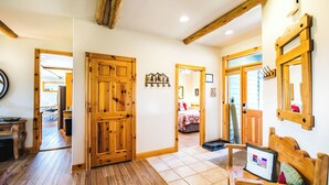 A wooden-floored hallway with a wooden door, a bench, and a mirror on the wall. - Golf Course Mountain Home , Views/Hot Tub/Star Gazing/Ski/Hike/Golf/Gather/Relax (Red Lodge)