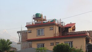A multi-story building with a red roof, balconies, and a water tank on the roof. - Goldenbirds Homestay (Pokhara)