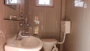 A small bathroom with a sink, toilet, and a window above the toilet. - Goldenbirds Homestay (Pokhara)