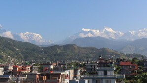 A town with buildings and snow-capped mountains in the background. - Goldenbirds Homestay (Pokhara)