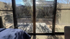 A room with a large sliding glass door leading to an outdoor area with a wooden deck and a view of a traditional building and trees.