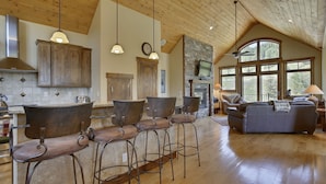 A spacious kitchen with wooden cabinets, a stone fireplace, and a large window overlooking the outdoors.
