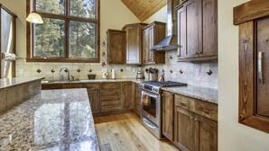 A kitchen with wooden cabinets, a granite countertop, a large window, and a built-in oven.