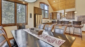 A dining area with a long table, wooden chairs, and a chandelier.