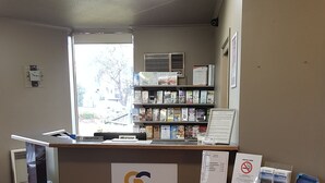 Bancada de recepção com placa indicando "Golden Chain Platinum", uma estante de livros, um relógio e uma janela com vista para edifícios lá fora.