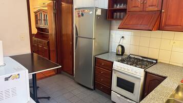 Una cocina funcional con refrigerador, estufa y armarios de madera.
