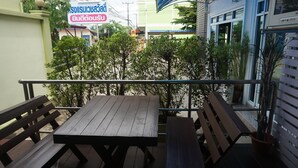 Ein Holztisch mit Bänken auf einem Balkon mit Blick auf ein Gebäude und Bäume.