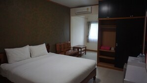 Ein Schlafzimmer mit Bett, einem Holznachttisch, Schreibtisch, Stuhl und Kleiderschrank.
