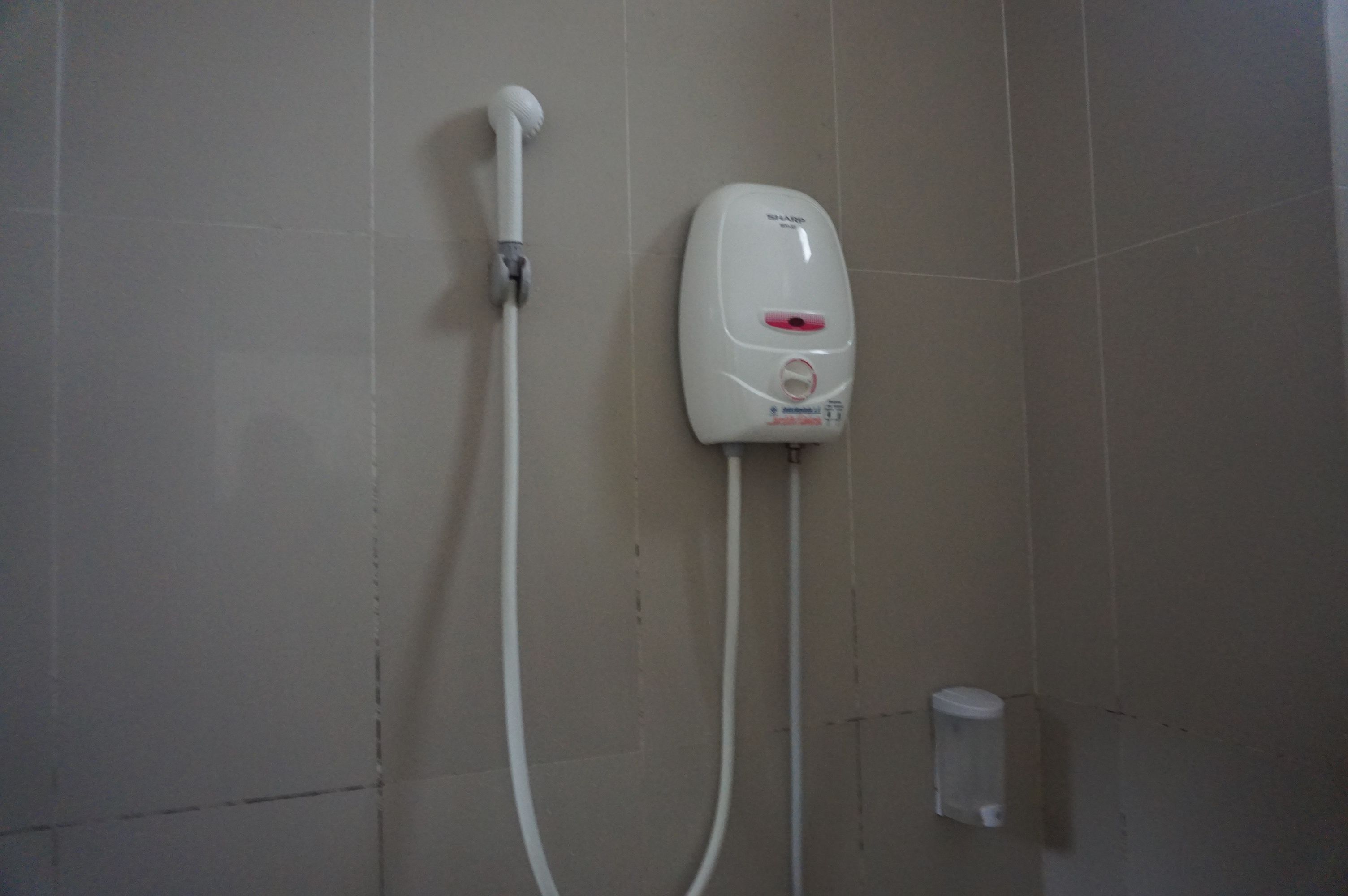 Une douche équipée d’un pommeau de douche à main et d’un distributeur de savon fixé au mur.