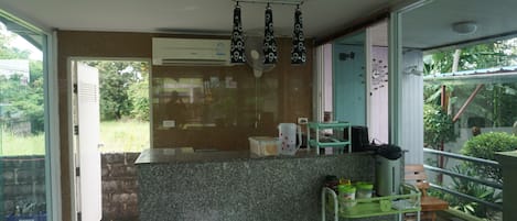 A modern kitchen with a granite countertop, a built-in air conditioner, and a small dining area with a chair and a table.