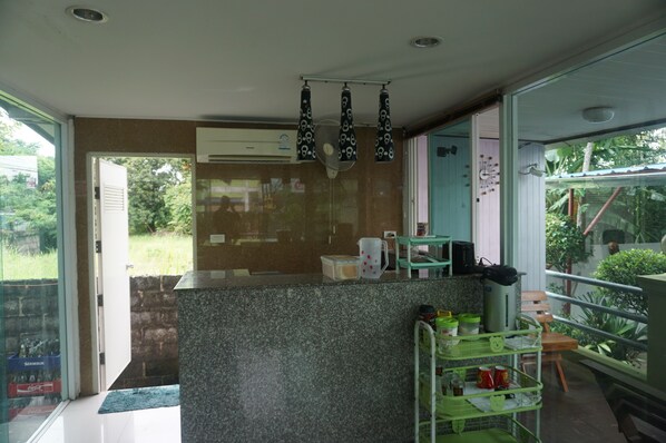 A modern kitchen with a granite countertop, a built-in air conditioner, and a small dining area with a chair and a table.