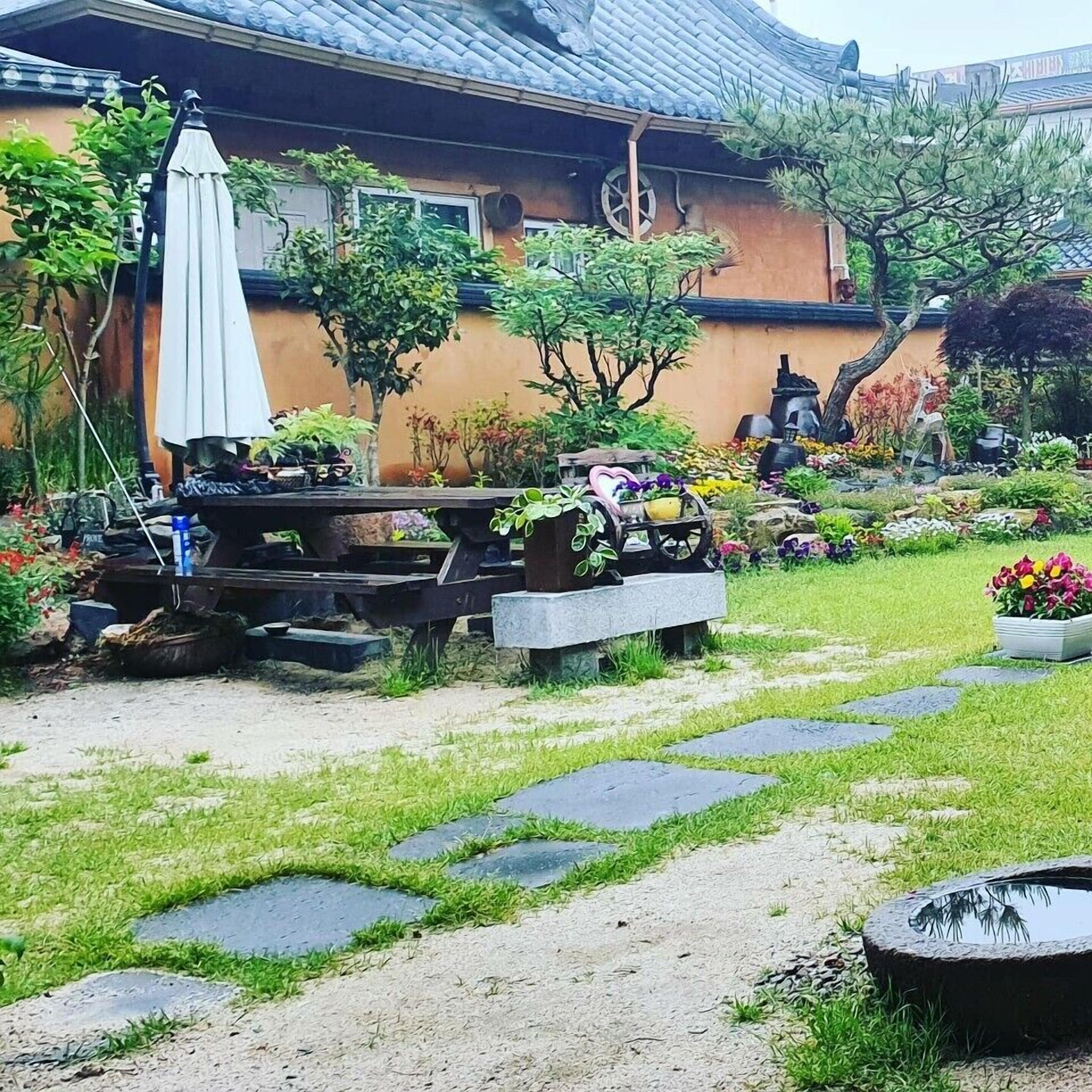A garden with a stone pathway, a picnic table, and a small pond.