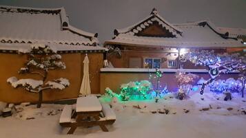 A traditional building with snow-covered roofs and a wooden bench in the foreground.
