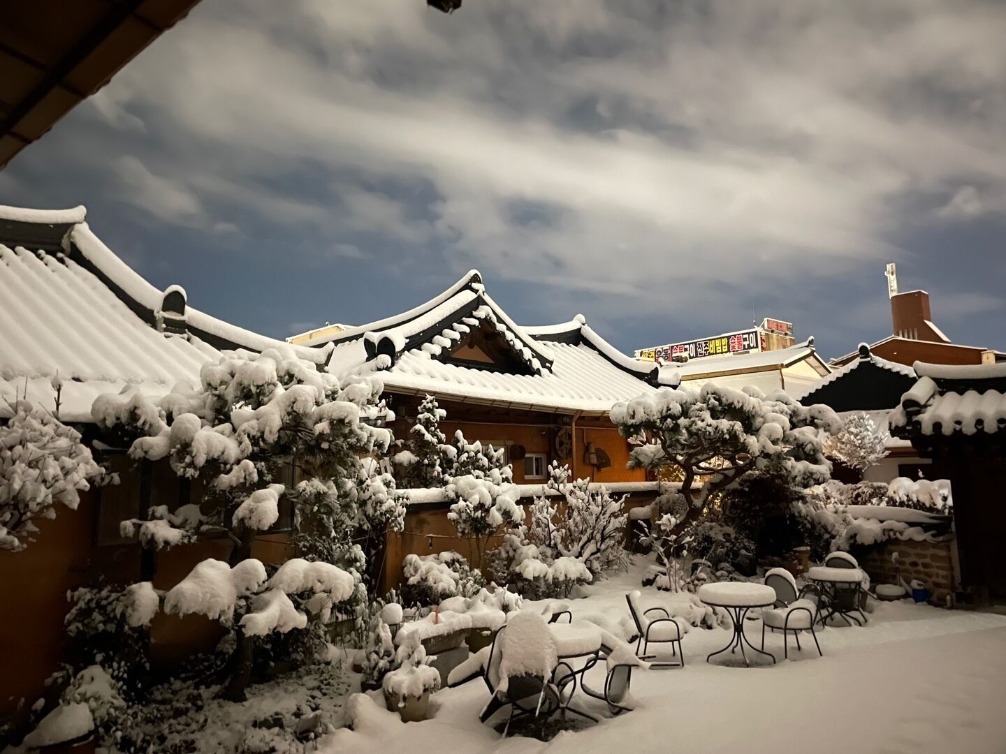 A traditional Japanese building with snow-covered roofs and a courtyard with outdoor seating.