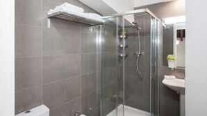 Une salle de bain moderne avec une douche à parois de verre, un lavabo blanc et un porte-serviettes.