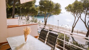 Un balcon avec une table et des chaises, donnant sur une plage et la mer.