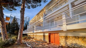 Un bâtiment moderne avec une façade en pierre, une porte en bois et un balcon doté de rampes en métal.