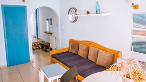Une pièce chaleureuse avec une porte bleue, un canapé en bois agrémenté de coussins, une petite table et une horloge murale.