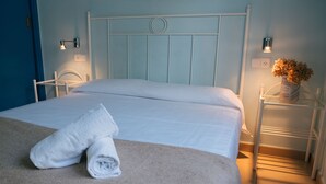Un lit bien fait, avec des draps blancs et une serviette enroulée posée sur le bord du lit.