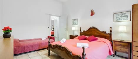Un dormitorio con una cama de madera, una mesita de noche, una lámpara y una silla.