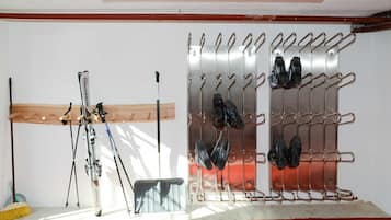 A ski rack with skis and poles, a broom, and a wooden shelf.