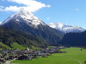 A mountain town with a prominent snow-capped peak, green fields, and a cluster of traditional buildings. - Double Room (Type A) - Greber Christine - Frühstückspension Fernblick (Schoppernau)