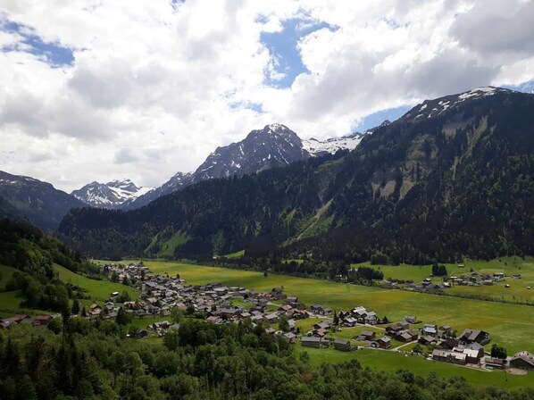 A mountainous village with houses and green fields.