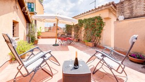 A patio with two lounge chairs, a table with a bottle and glasses, and a white umbrella. - Romantic House in Trastevere (Rome)