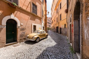 A narrow cobblestone street with a vintage car parked on the side. - Romantic House in Trastevere (Rome)