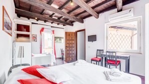 A hotel room with a large bed, a desk, a chair, and a TV. - Romantic House in Trastevere (Rome)