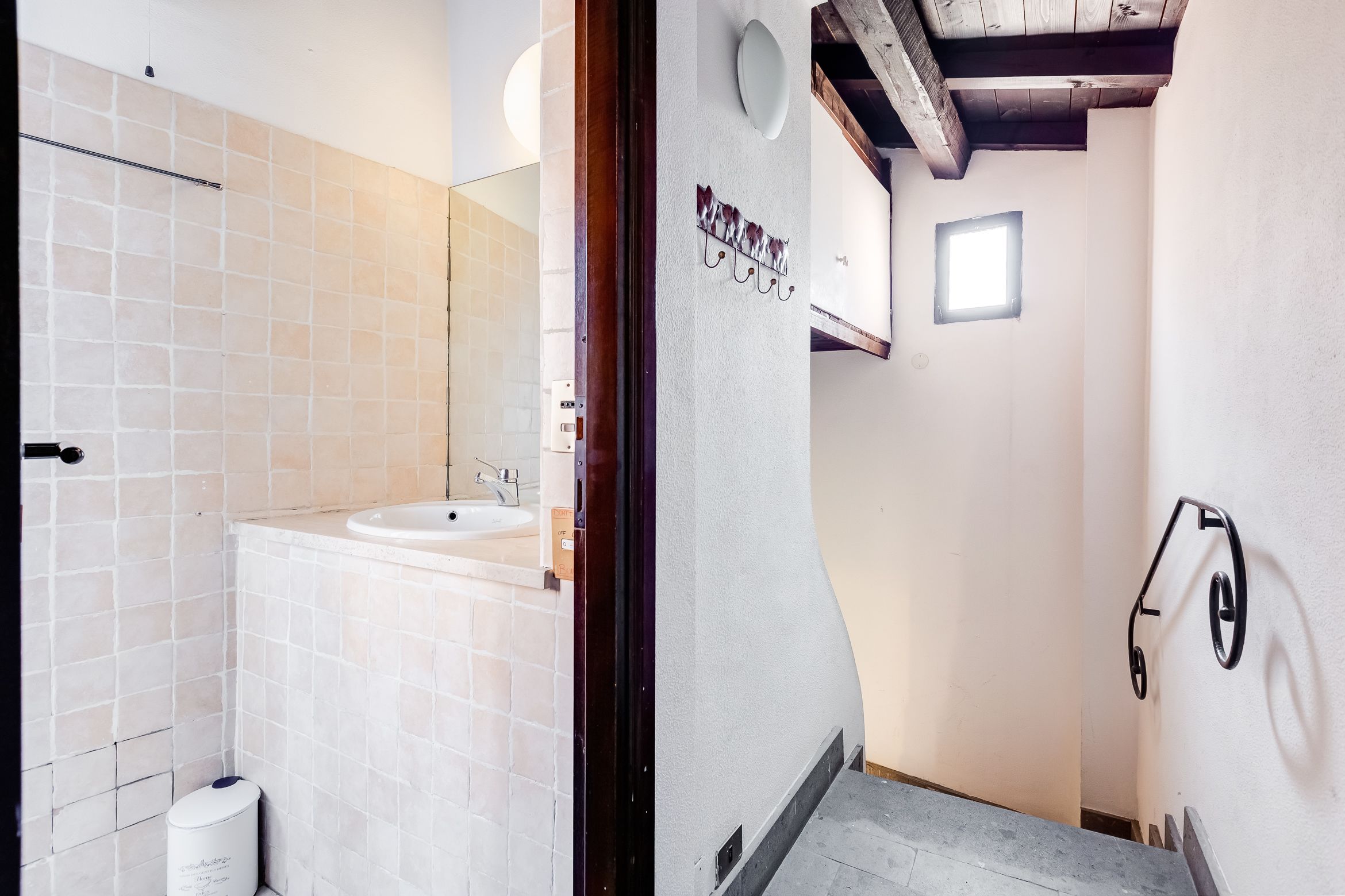 A bathroom with a white sink, tiled walls, and a small window.