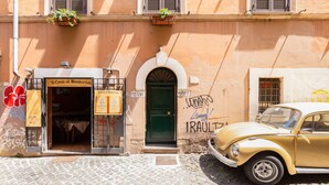 A vintage car parked in front of a building with a sign reading "Il Conte di Montecristo." - Romantic House in Trastevere (Rome)