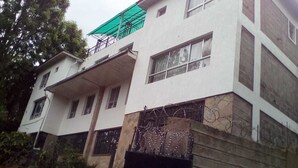 Un edificio de varios pisos con fachada blanca, múltiples ventanas y un toldo verde en el nivel superior.