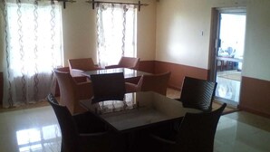 Un comedor con una mesa y sillas, una ventana con cortinas y vistas al exterior.