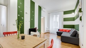 Un salón moderno con un sofá gris, cojines rojos y una mesa de comedor de madera con sillas.