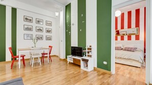 Una sala de estar moderna con comedor, televisor y una cama con cortinas a rayas.