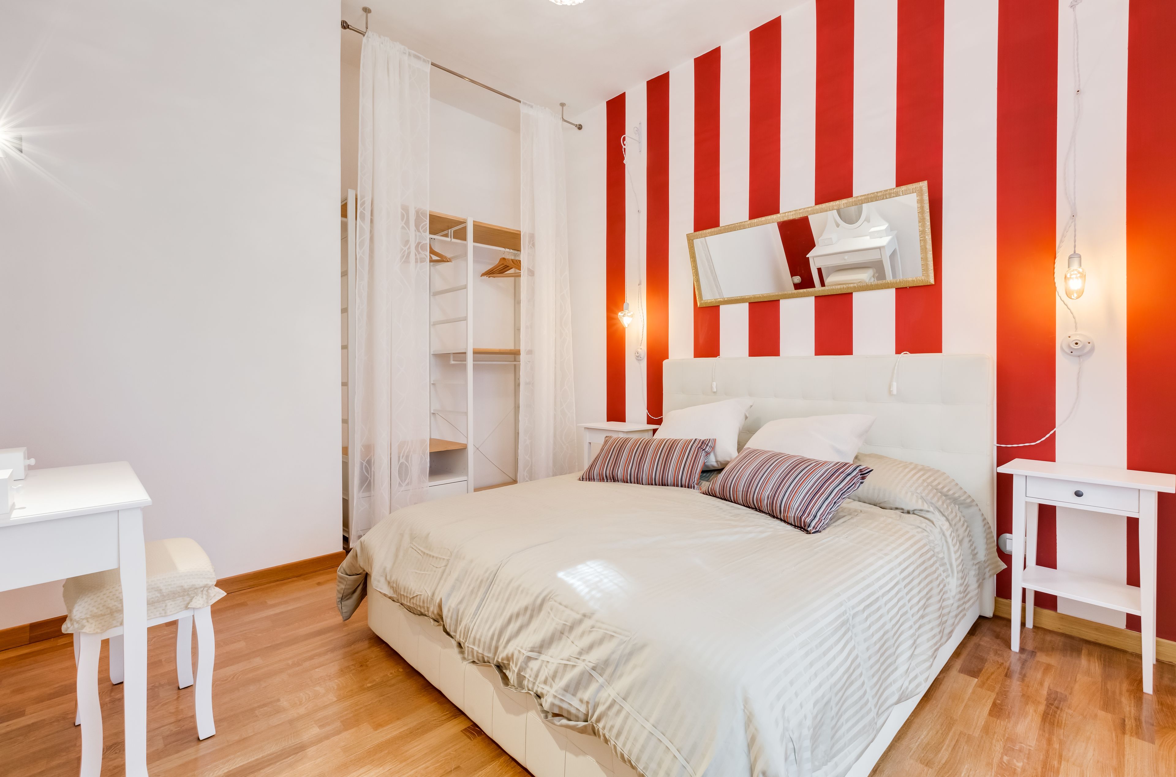 A bedroom with a bed, bedside tables, a desk, and a wardrobe.