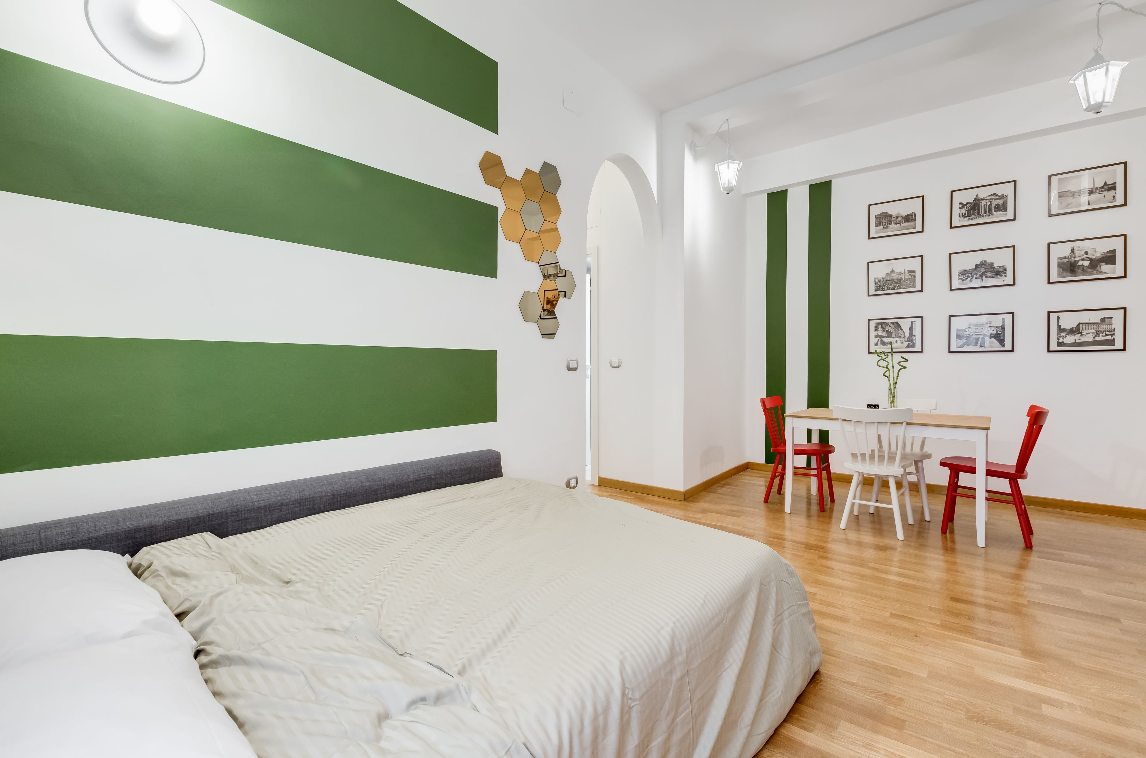 A hotel room with a bed, a desk with chairs, and a wall with framed pictures.