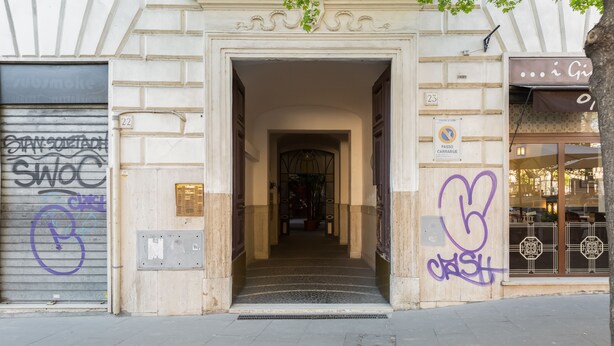 Una entrada a un edificio con una puerta metálica y un letrero que indica zona de prohibido estacionar.