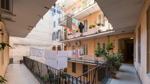 Un edificio residencial de varios niveles con balcones, plantas en macetas y ropa tendida.