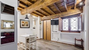 A room with a wooden ceiling, a white table with chairs, a wardrobe, and a window with a geometric pattern. - Pellegrino Campo de' Fiori Suite (Rome)