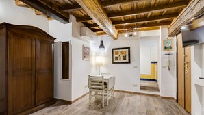 A room with a wooden wardrobe, a dining table with chairs, a hanging lamp, and a framed picture on the wall. - Pellegrino Campo de' Fiori Suite (Rome)
