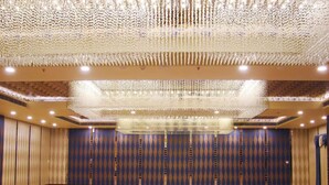 A large, empty conference room with patterned carpet, a high ceiling with a decorative chandelier, and patterned walls. - Hotel Grand Maple (Jaipur)