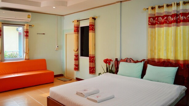 A hotel room with a bed, a sofa, curtains, and a window. - Rachiga Hotel Grand Resort (Sawang Daen Din)